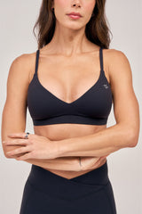 Front view of a woman wearing the BODY FOCUSED Core Bare Top sports bra in black, arms crossed